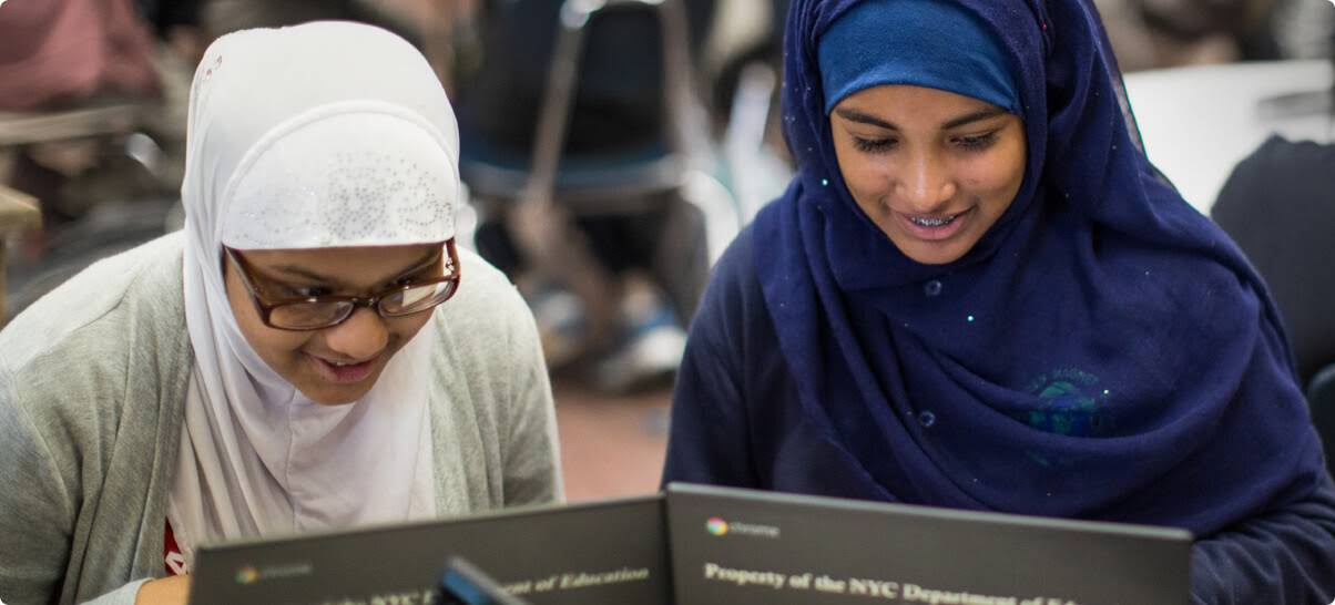 Duas alunas usando niqabs com Chromebooks