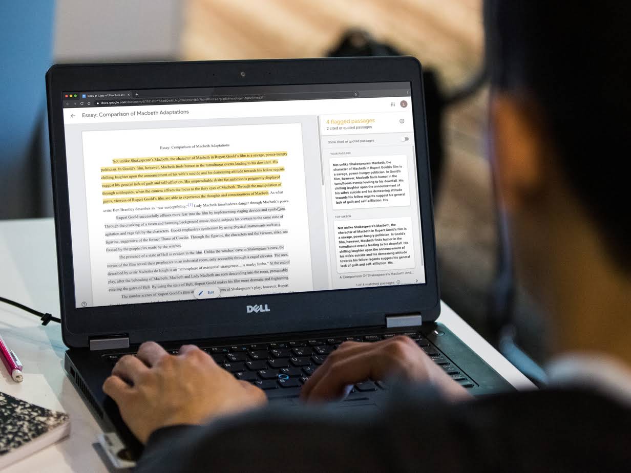 En elevs händer skriver på en Chromebook. På skärmen ser vi hur eleven arbetar med en uppsats med flaggade stycken i högerkolumnen.