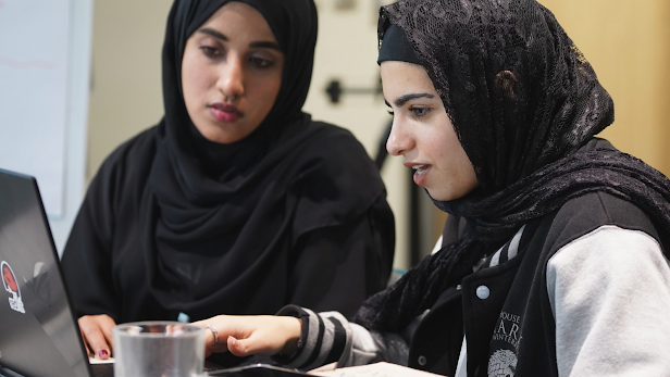 Dos mujeres en hijabs trabajan juntas en una computadora portátil