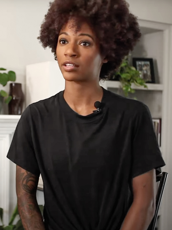 Fotografía cercana de una mujer con afro vestida en una camisa negra