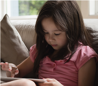 Young girl sitting on a sofa, using an Android tablet