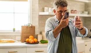 En man i ett kök läser en etikett med hjälp av sin Android-telefon.