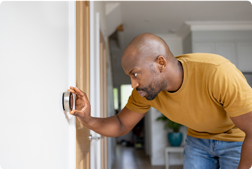 A homeowner adjusting the temperature on his Nest thermostat.