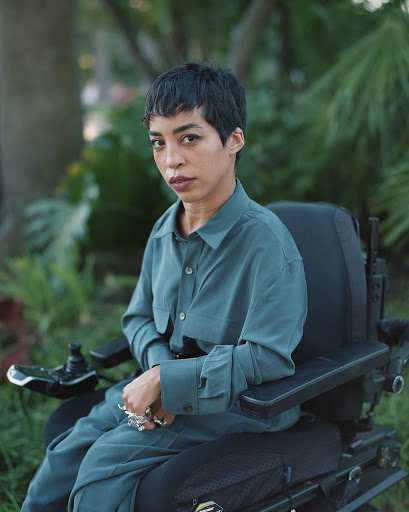 Jillian Mercado, fundadora de Disabled Black Creatives en su silla de ruedas vistiendo una camisa de seda verde azulado.