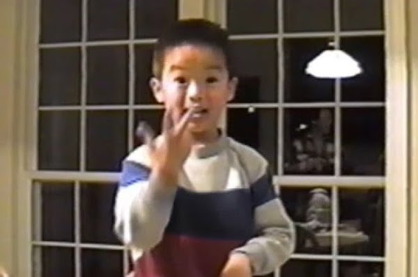 Foto familiar de un joven asiático con un suéter a rayas usando lenguaje de señas