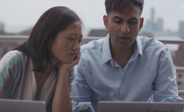 Man and woman working together in front of laptops.