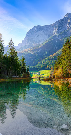 Una foto de un lago de montaña, dividida por la mitad de forma vertical. El lado izquierdo se ve en Ultra HDR, con colores intensos y nítidos, mientras que el lado derecho se ve en definición estándar.