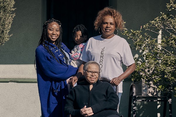 Family portrait of Keiara with her daughter, mother, and grandmother in front of the home they share.