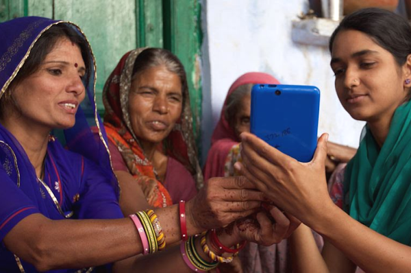 Cuatro mujeres indias con ropa tradicional india miran juntas al teléfono inteligente