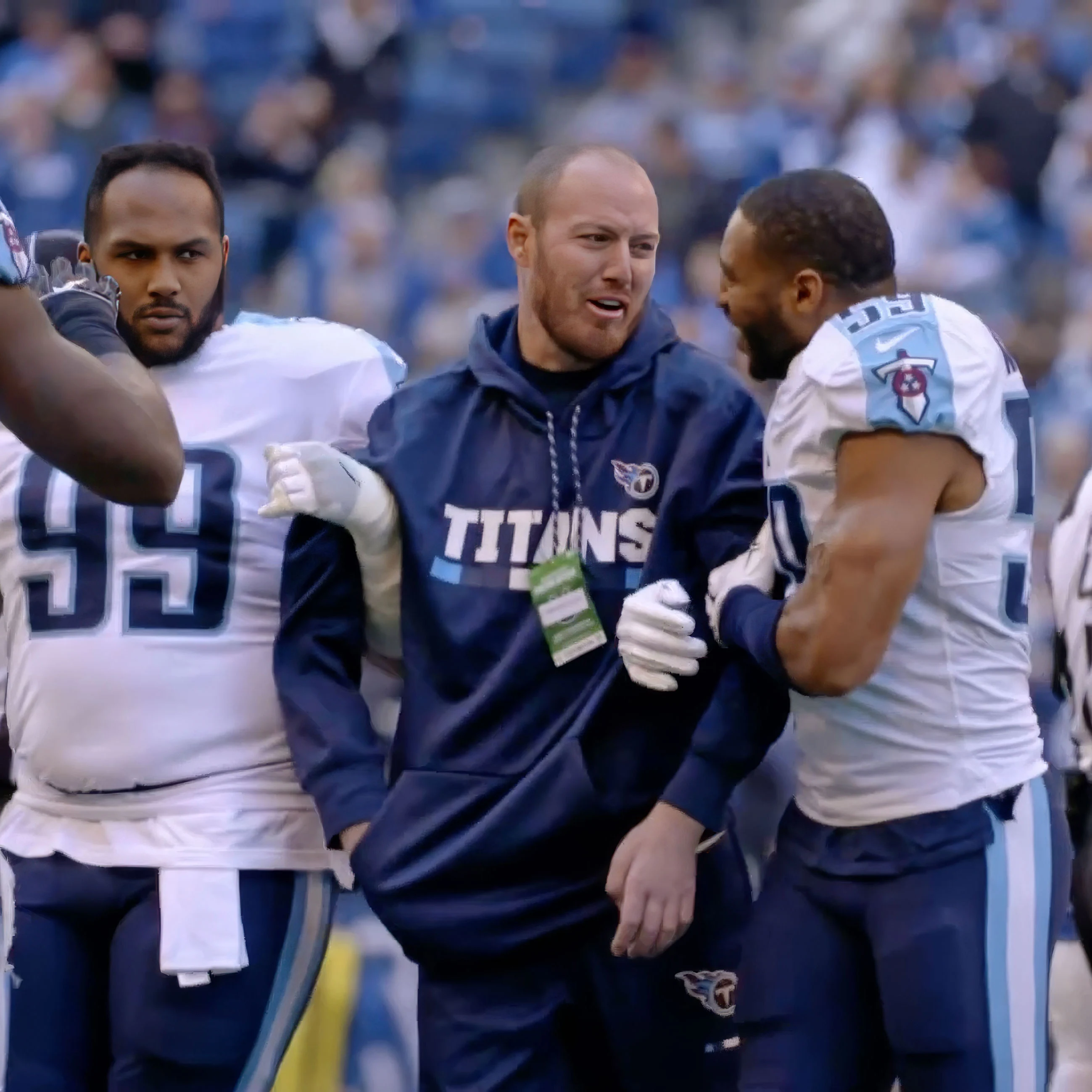 Thumbnail of Tim Shaw, former NFL player, standing in a between two other Titans players at a game.