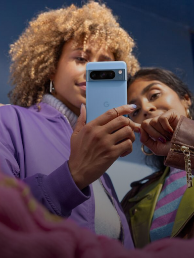 兩位 Android 使用者看著一部手機，其中一位使用者指著螢幕上的短訊回應。