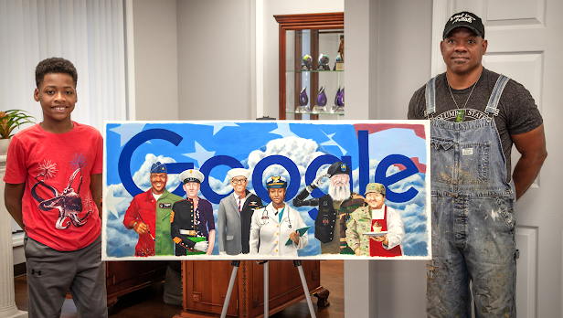 Un hombre y su hijo de pie junto a una impresión de un Doodle de Google que muestra a seis veteranos de diferentes ramas militares