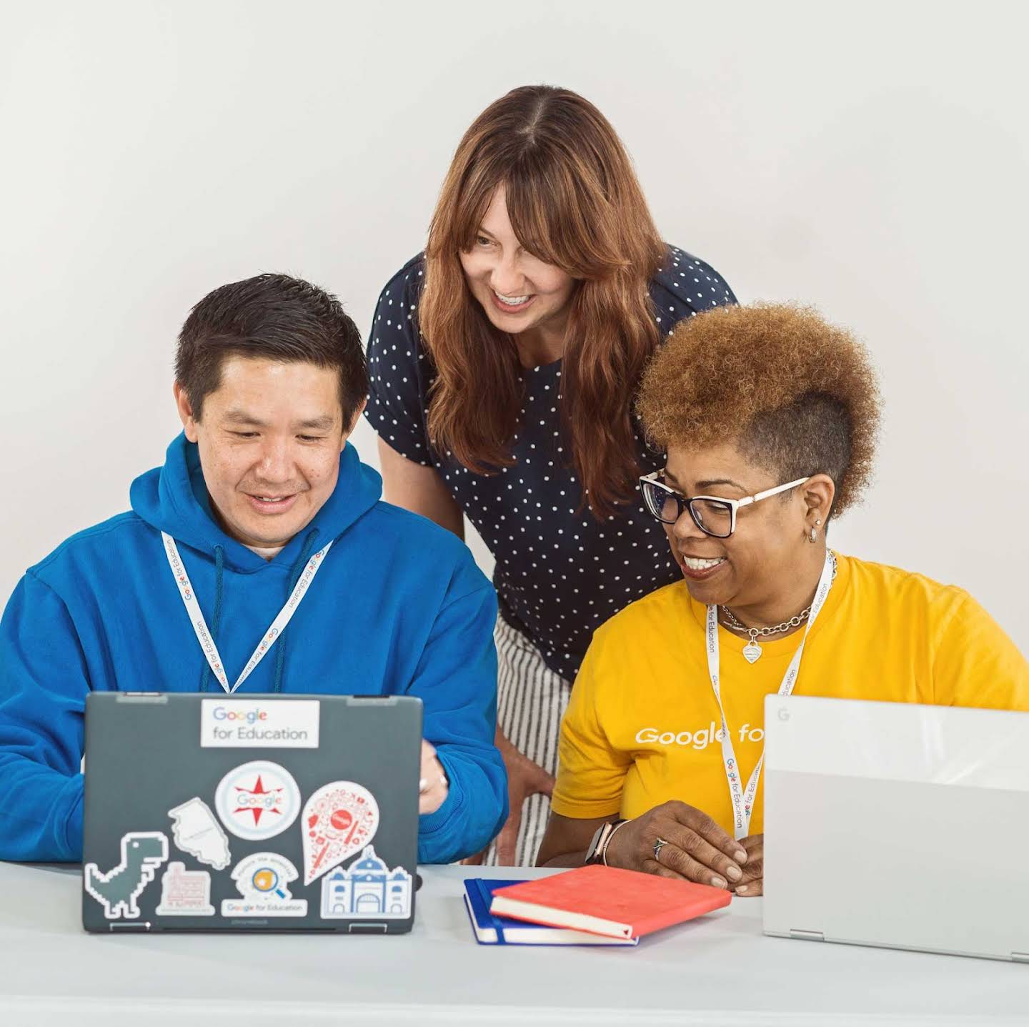 Imagem de três educadores colaborando juntos em volta de um Chromebook