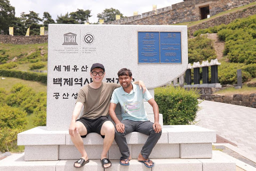 Dnyan and Kyehyun pose together, arm in arm, in front of a monument.