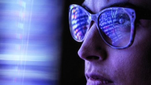 Woman with digital code reflecting in glasses