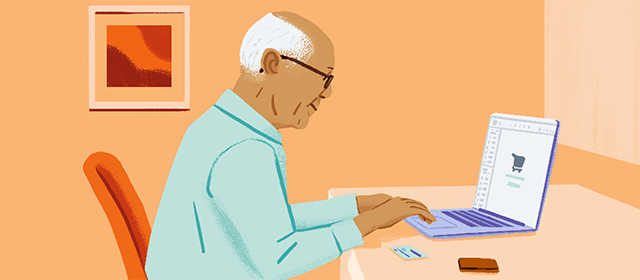 Starší muž, který sedí na stole a využívá platební kartu k nákupu v notebooku.